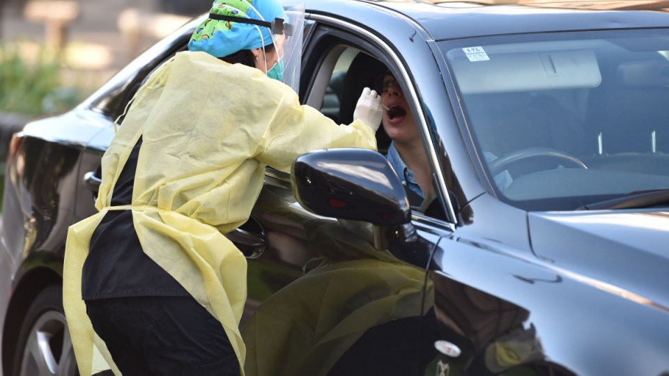 A medic takes a nasal swab from a driver at a drive-through testing centre for the COVID-19 coronavirus in Sydney