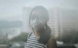 Young woman wearing protective face mask in city due to the polluted air