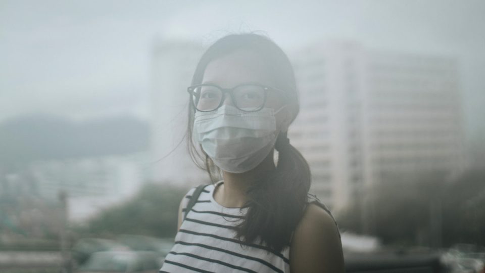Young woman wearing protective face mask in city due to the polluted air