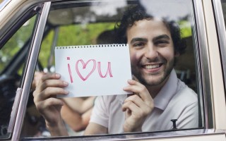 Man in car holding sign saying 'I love you' -