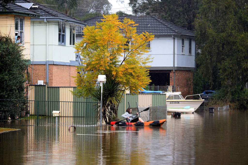 A resident paddles a kayak to commute from her flooded residential area near the overflowing Hawkesbury River in the northwestern Sydney suburb of Windsor on July 6, 2022.