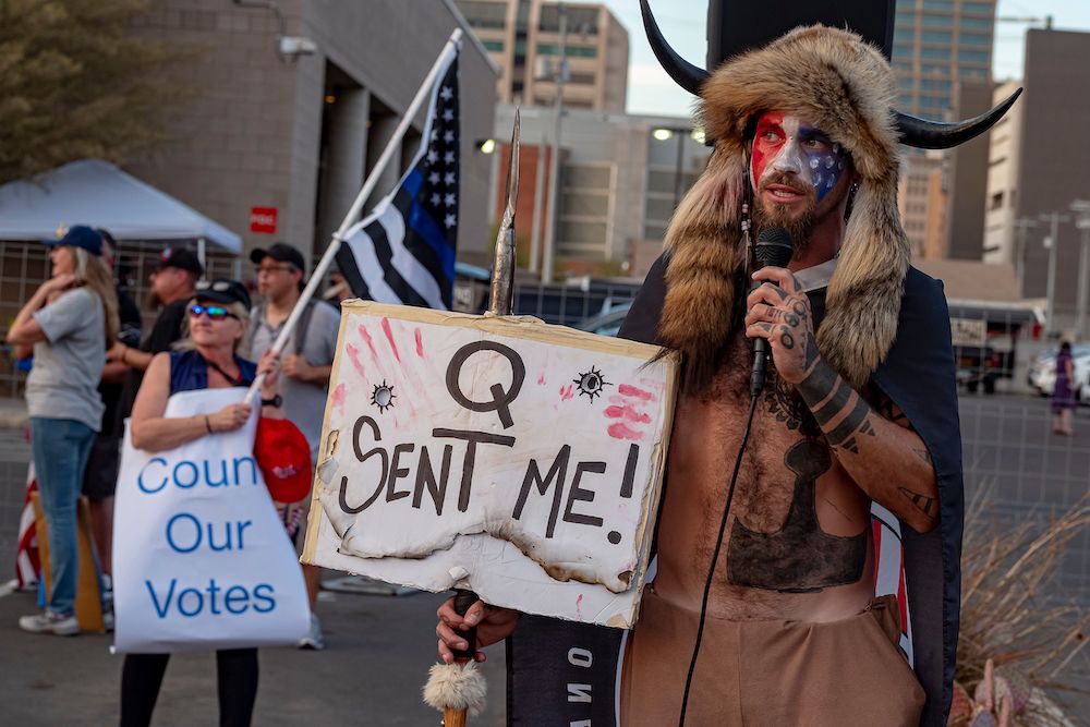 Jake Angeli, known as the "QAnon Shaman," holds a sign reading "Q Sent Me" as supporters of US President Donald Trump gather to protest