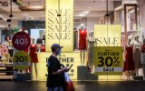 Pictured is a shopper walking past a shop displaying sales signs during the Boxing Day sales on December 26