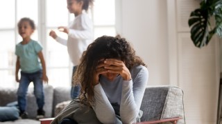 Sad mother and playful children at home