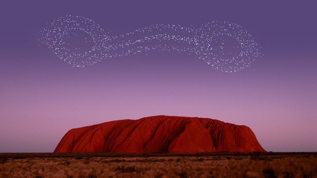 Drones fly over Uluru at sunset, creating images of light in the sky. <i>Photo: Voyages Indigenous Tourism Australia</i>