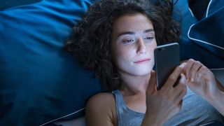 pictured is someone in bed to illustrate how phones impact sleep